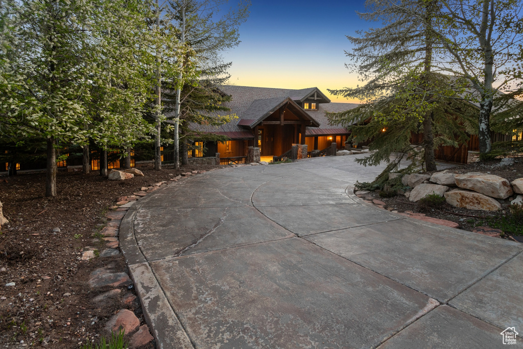 Rustic home featuring curved driveway and a shingled roof