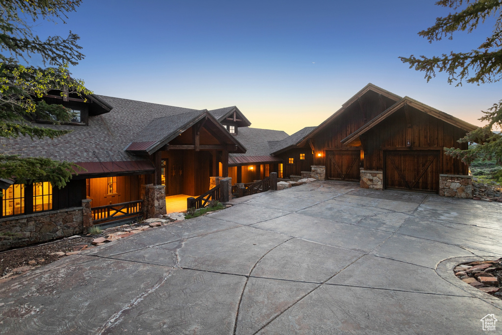Chalet / cabin with concrete driveway, a garage, board and batten siding, and stone siding
