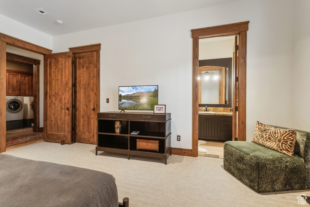 Carpeted bedroom featuring washer and clothes dryer, a sink, and ensuite bathroom