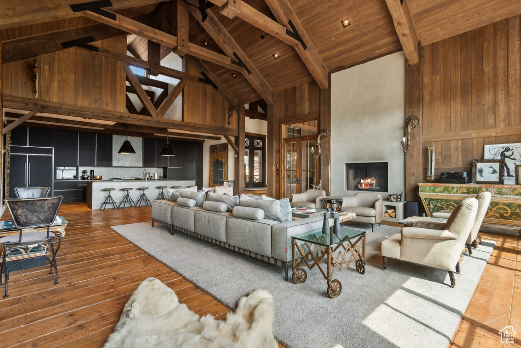 Living room featuring high vaulted ceiling, wood ceiling with exposed beams, dark wood-style flooring, and wooden walls