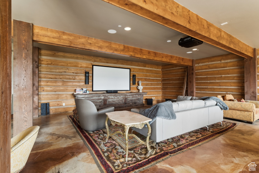 Home theater featuring finished concrete flooring, recessed lighting, and log walls