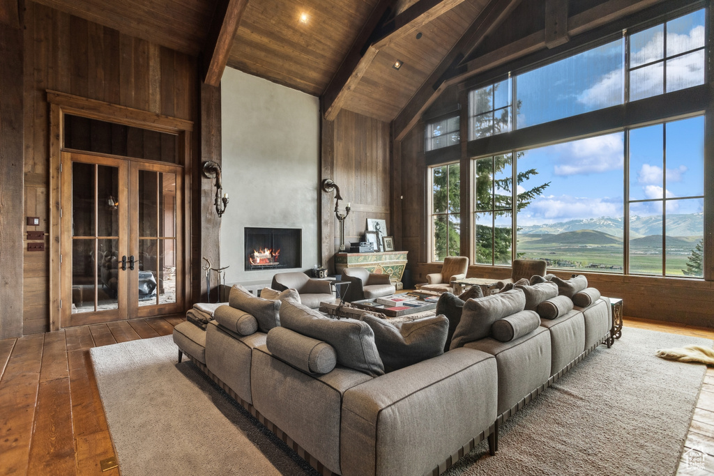 Living room featuring high vaulted ceiling, wood ceiling with exposed beams, hardwood / wood-style flooring, a mountain view, and wood walls