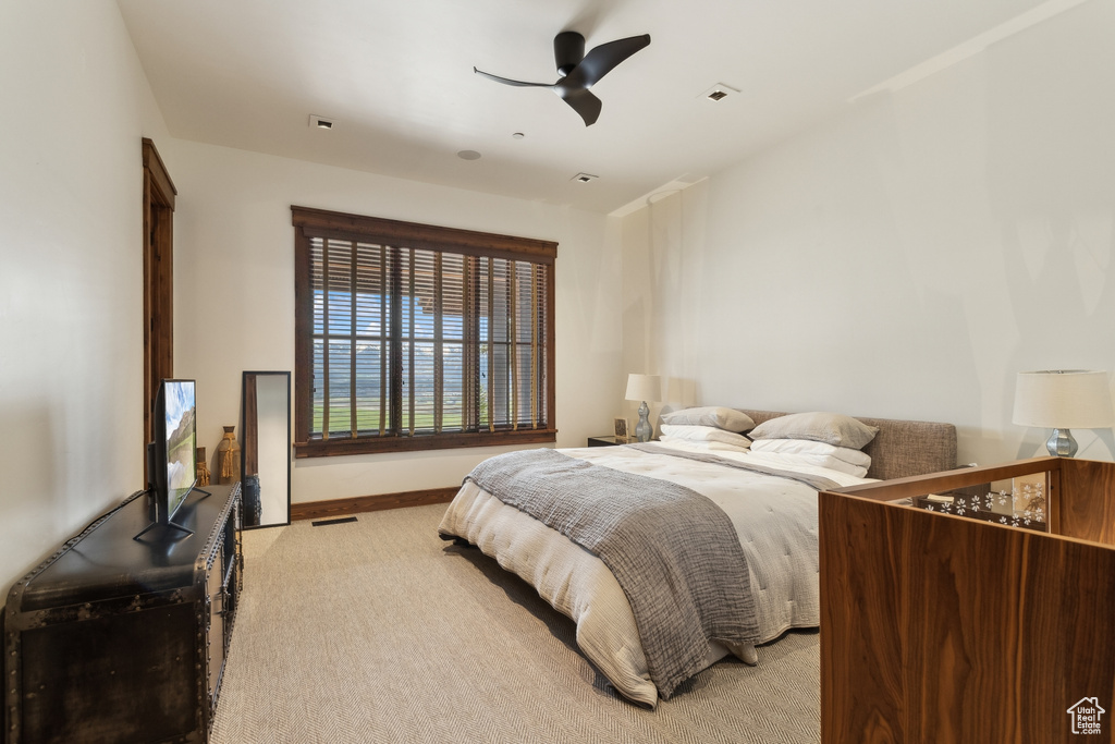 Bedroom featuring light colored carpet, baseboards, and ceiling fan