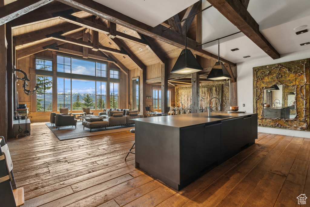 Kitchen with a sink, dark wood finished floors, beam ceiling, dark cabinetry, and high vaulted ceiling