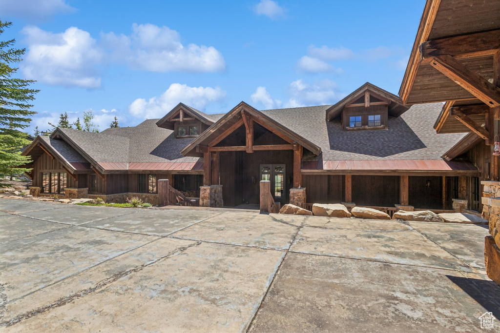 View of front of property with roof with shingles and stone siding