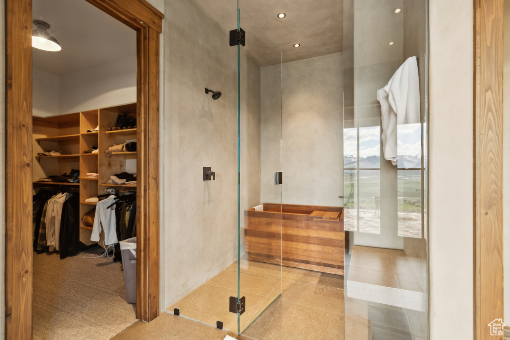 Bathroom with a stall shower, a walk in closet, and tile patterned floors