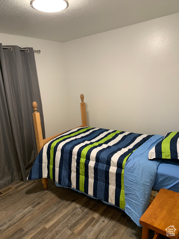 Bedroom with wood finished floors and a textured ceiling