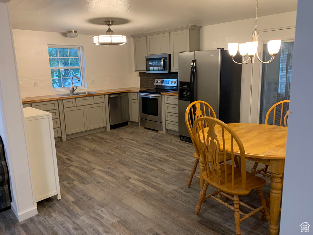Kitchen featuring stainless steel appliances, wooden counters, a sink, dark wood-style flooring, and backsplash