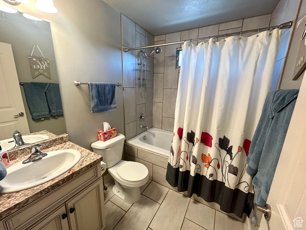 Full bathroom with toilet, tiled shower / bath combo, vanity, and tile patterned floors
