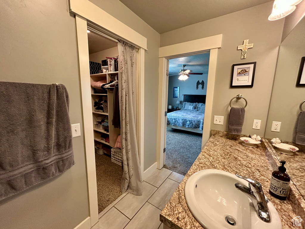 Ensuite bathroom featuring vanity, ceiling fan, and a closet
