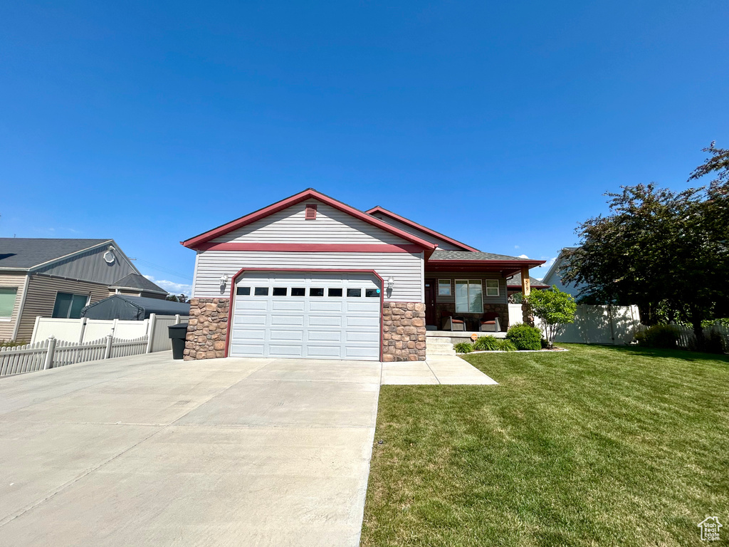 Single story home with driveway, stone siding, an attached garage, and a porch
