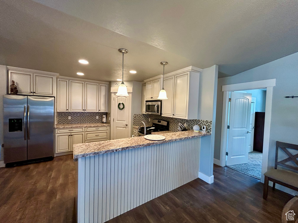 Kitchen with stainless steel appliances, dark wood-style flooring, a peninsula, tasteful backsplash, and recessed lighting
