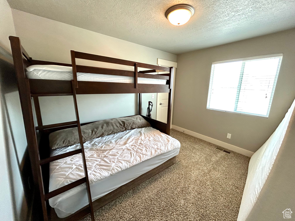 Bedroom featuring a textured ceiling, baseboards, and carpet floors
