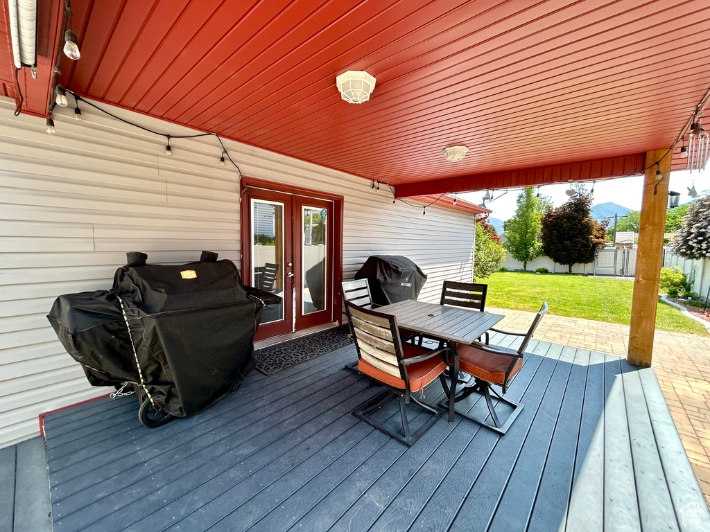Wooden deck with french doors, outdoor dining space, and grilling area