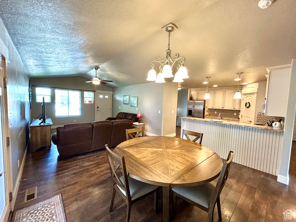 Dining room featuring dark wood-style flooring, ceiling fan, a textured ceiling, baseboards, and lofted ceiling