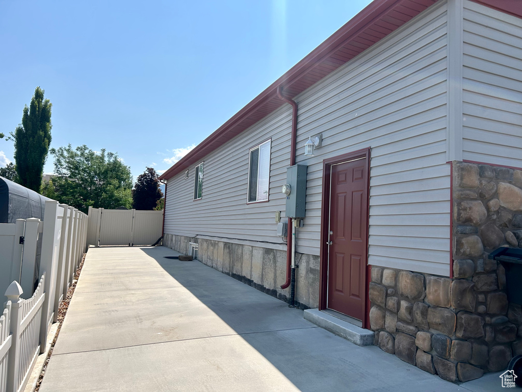 View of side of property with a fenced backyard, stone siding, and a patio area