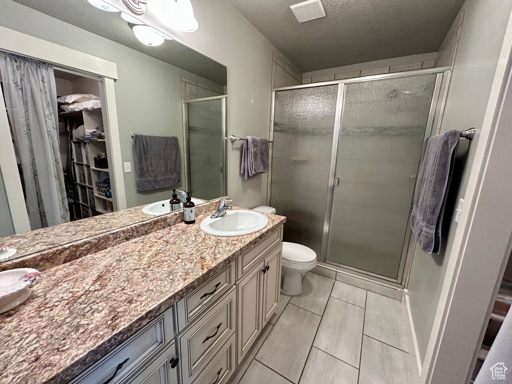 Full bath featuring vanity, a shower stall, a spacious closet, and toilet