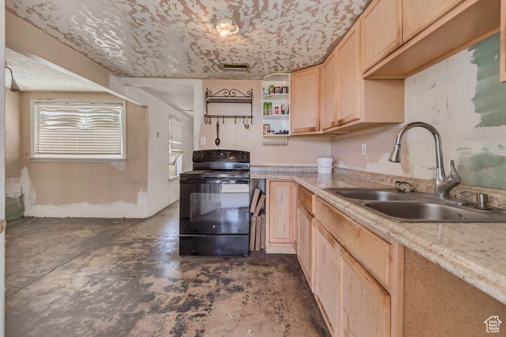 Kitchen with black electric range, a sink, light brown cabinets, unfinished concrete floors, and open shelves