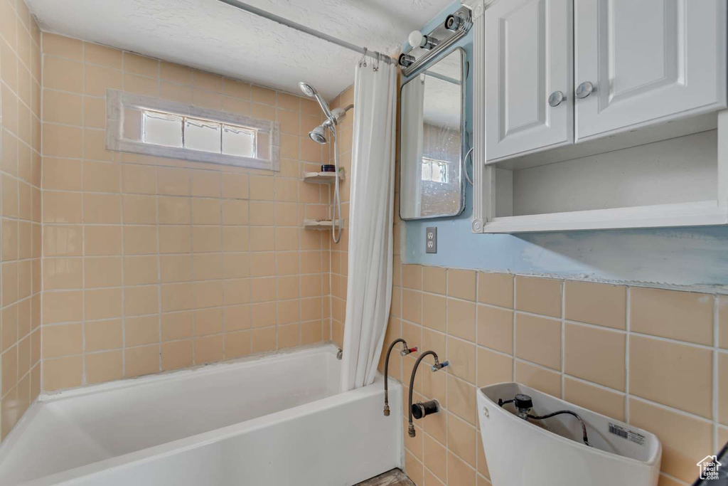 Bathroom with shower / bath combo with shower curtain and tile walls