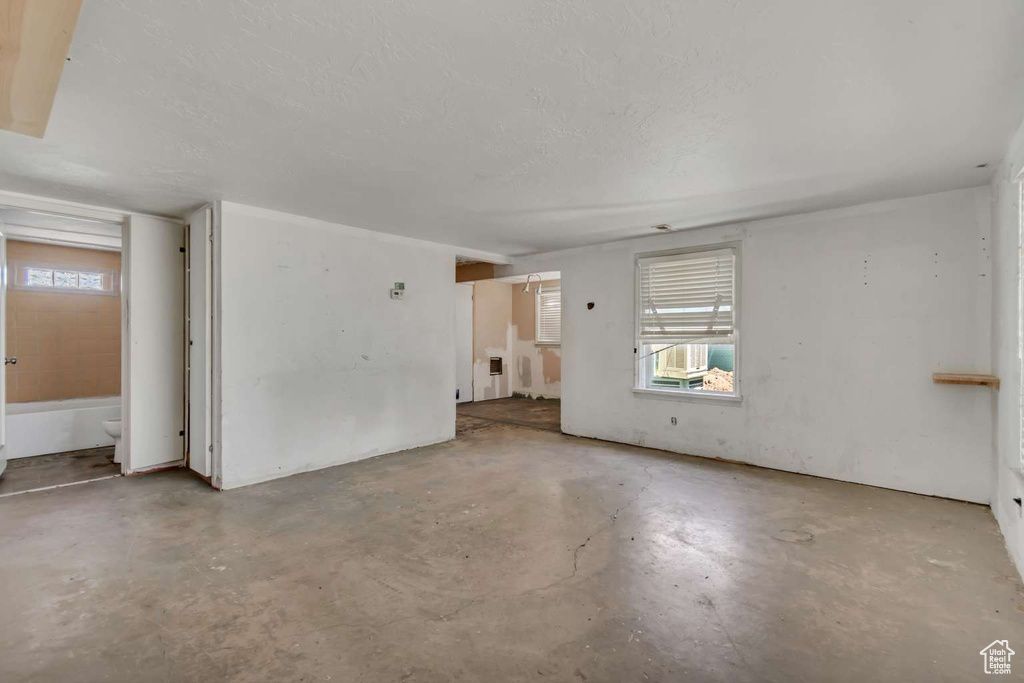 Unfurnished room featuring unfinished concrete flooring and plenty of natural light