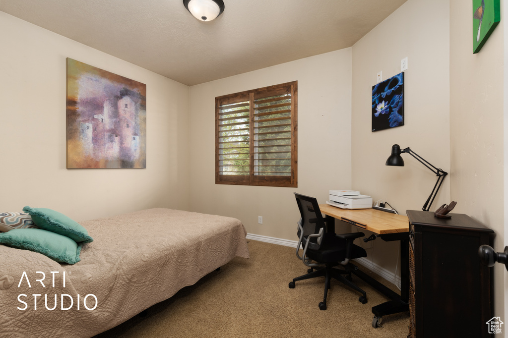 Carpeted bedroom featuring baseboards and a desk