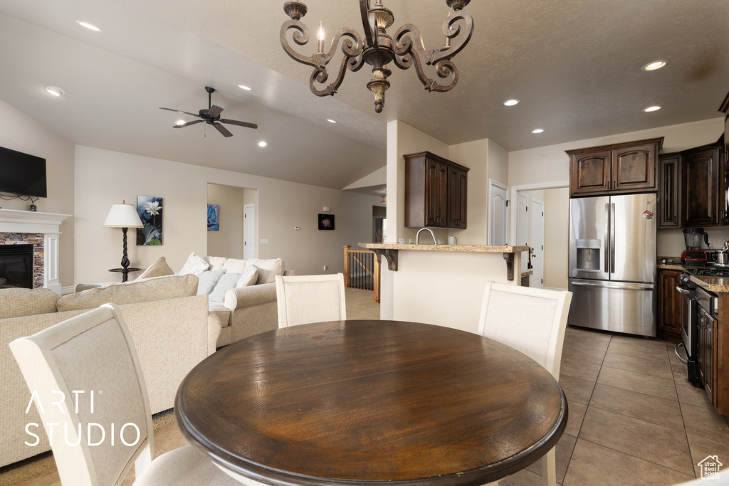 Dining space featuring recessed lighting, ceiling fan, vaulted ceiling, a chandelier, and a fireplace