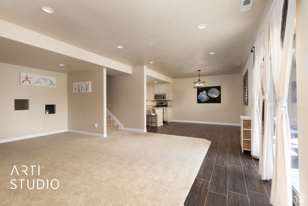 Unfurnished living room with recessed lighting, baseboards, stairs, dark wood finished floors, and a chandelier