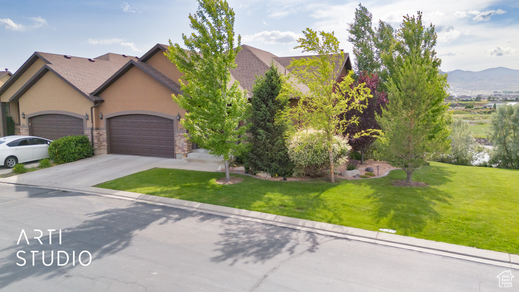 View of front of house with stucco siding, an attached garage, a front yard, and concrete driveway