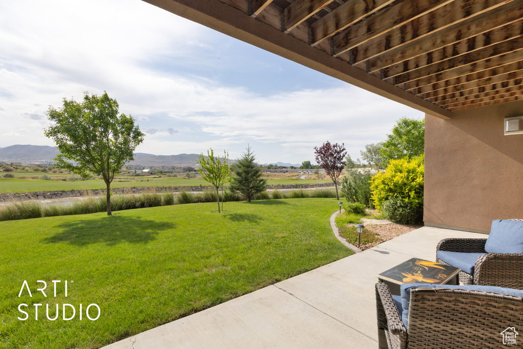 View of grassy yard featuring a patio area and a water and mountain view