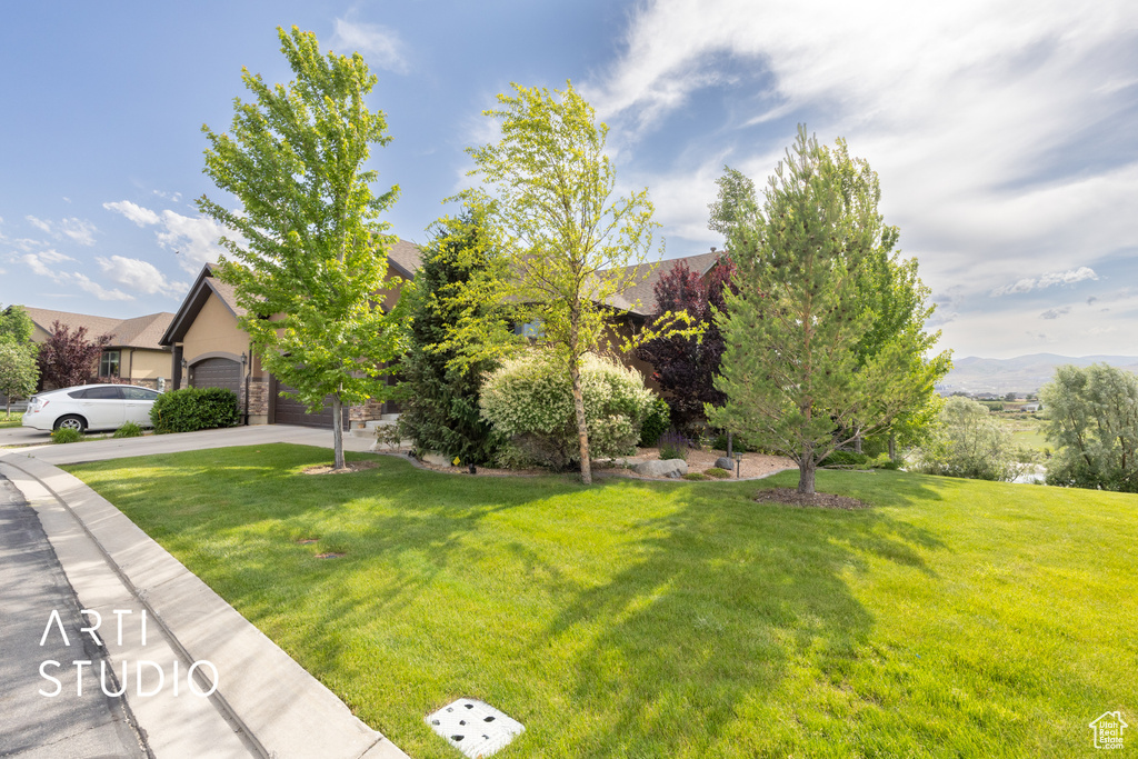 View of front of home featuring concrete driveway, a front yard, an attached garage, and a mountain view