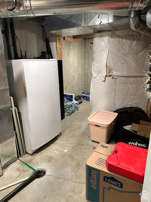 Unfinished below grade area featuring freestanding refrigerator