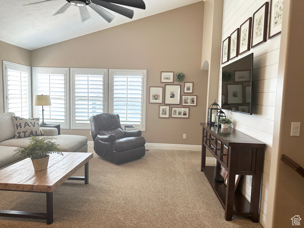 Living area featuring vaulted ceiling, ceiling fan, carpet, and baseboards
