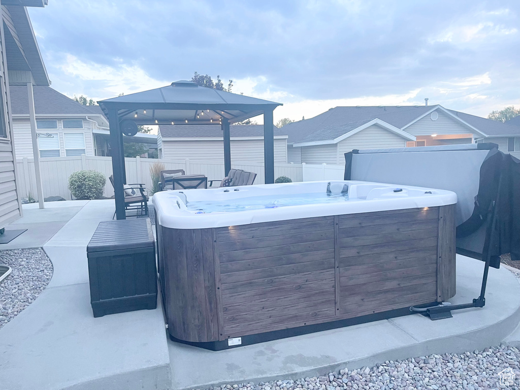 Fenced backyard featuring a hot tub, a gazebo, and a patio area