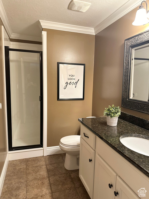 Full bath with vanity, toilet, a stall shower, ornamental molding, and a textured ceiling