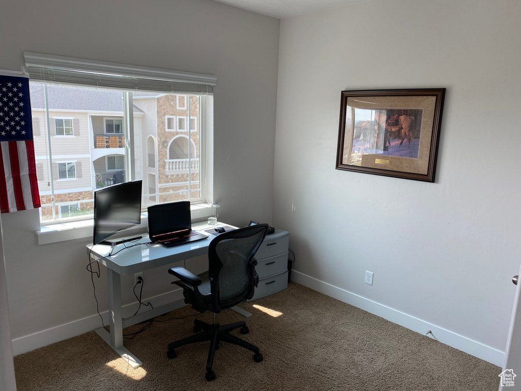 Carpeted home office featuring baseboards