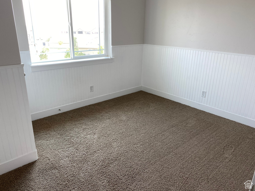Spare room featuring carpet and wainscoting