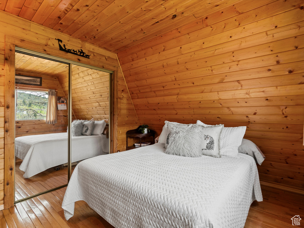 Bedroom featuring wood-type flooring, a closet, wooden ceiling, and wooden walls