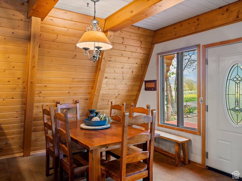 Dining area featuring wood walls and wooden ceiling with exposed beams