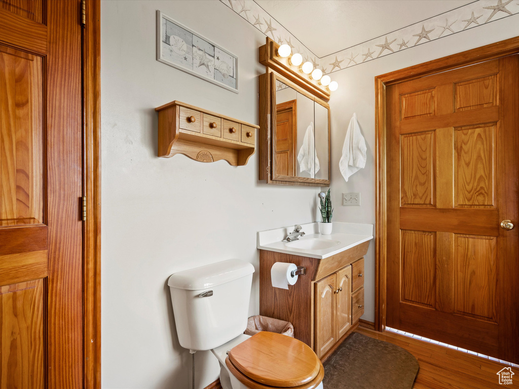 Bathroom with vanity, toilet, and wood finished floors
