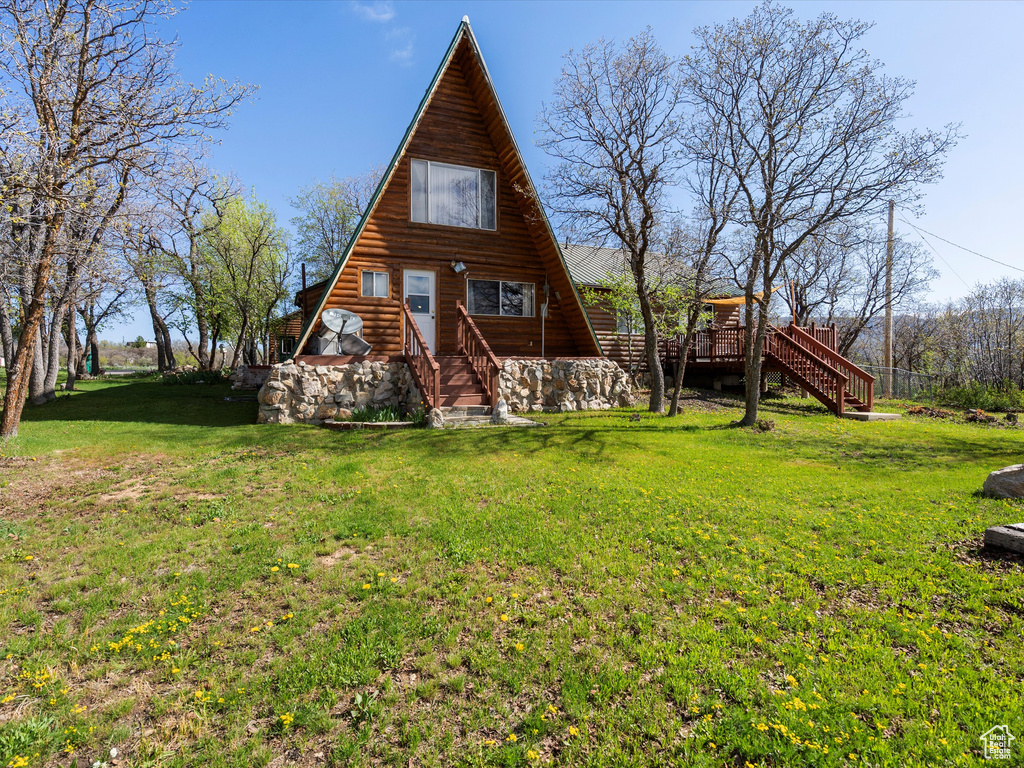 Rear view of house featuring stairs, a yard, a deck, and log exterior