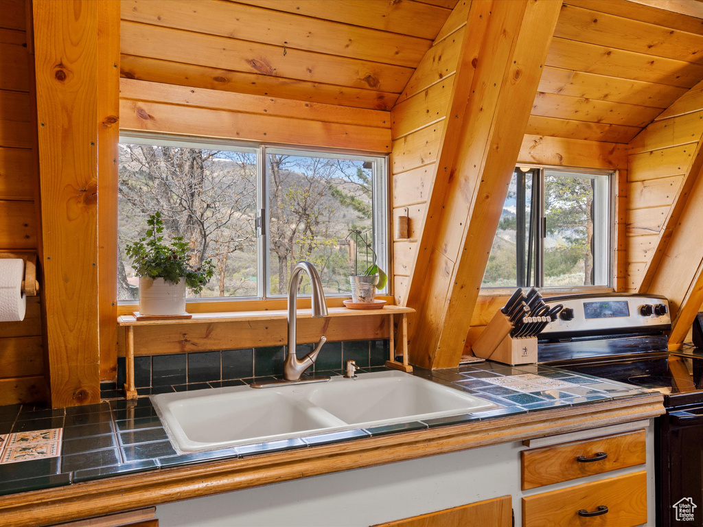 Kitchen featuring stainless steel electric range oven, vaulted ceiling, a sink, plenty of natural light, and wooden ceiling