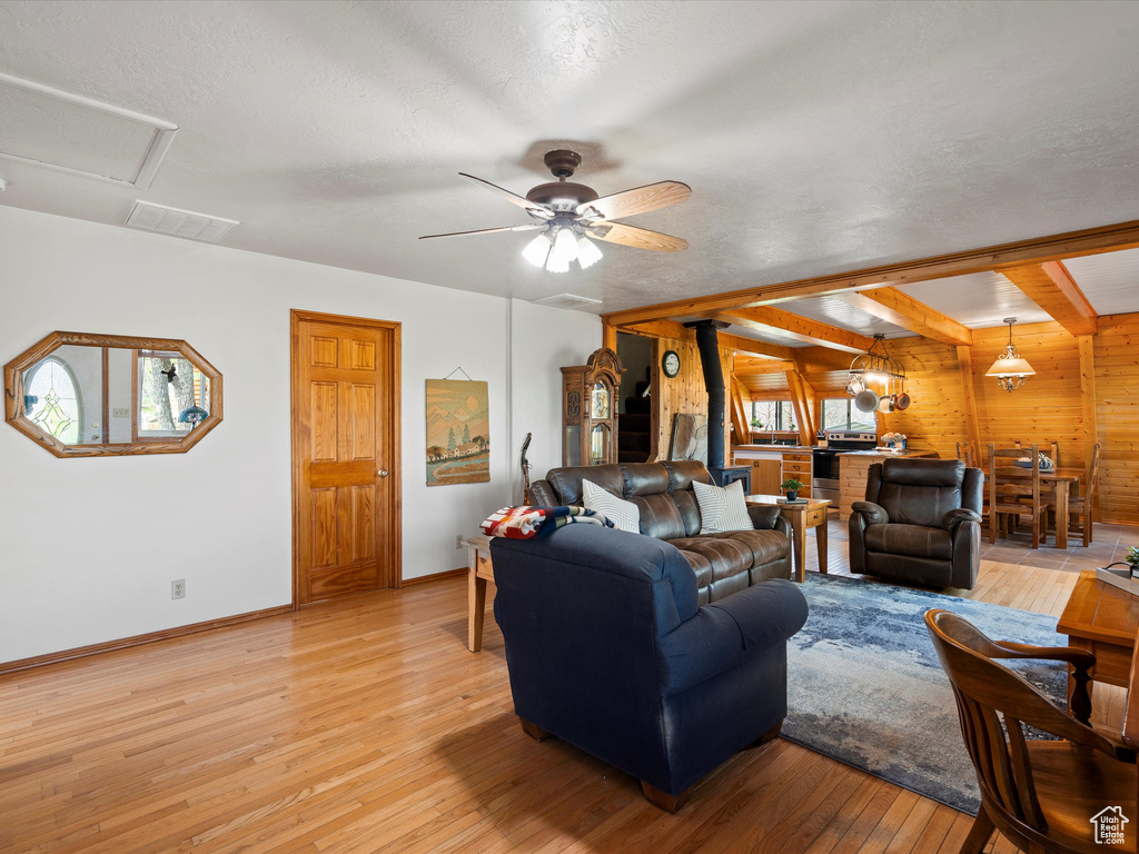 Living room with wooden walls, light wood-type flooring, baseboards, and plenty of natural light