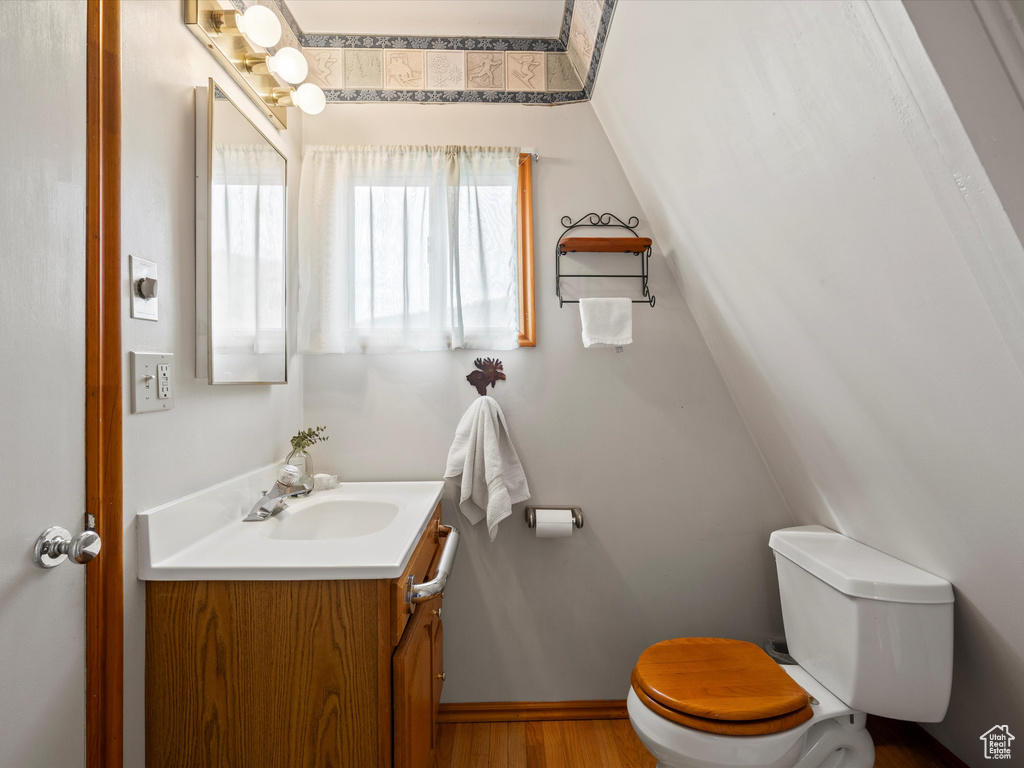Bathroom featuring toilet, vanity, wood finished floors, and baseboards