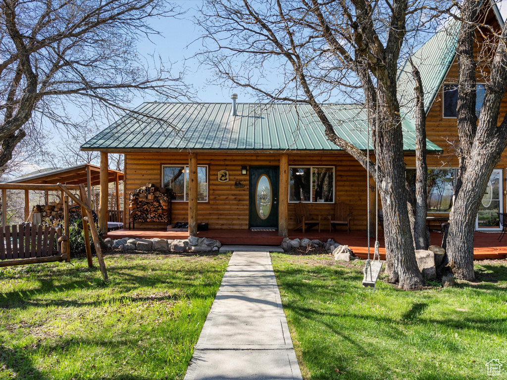 View of front facade featuring covered porch, faux log siding, and a front yard