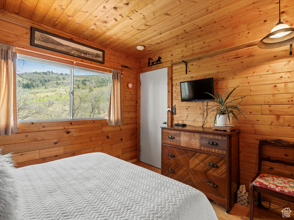 Bedroom featuring wooden walls, light wood-style flooring, and wooden ceiling