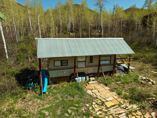 Back of property with metal roof and a view of trees