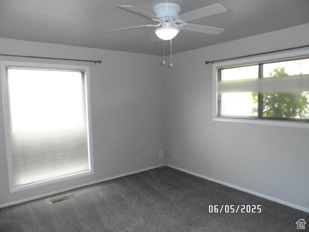 Spare room featuring dark carpet, ceiling fan, and baseboards