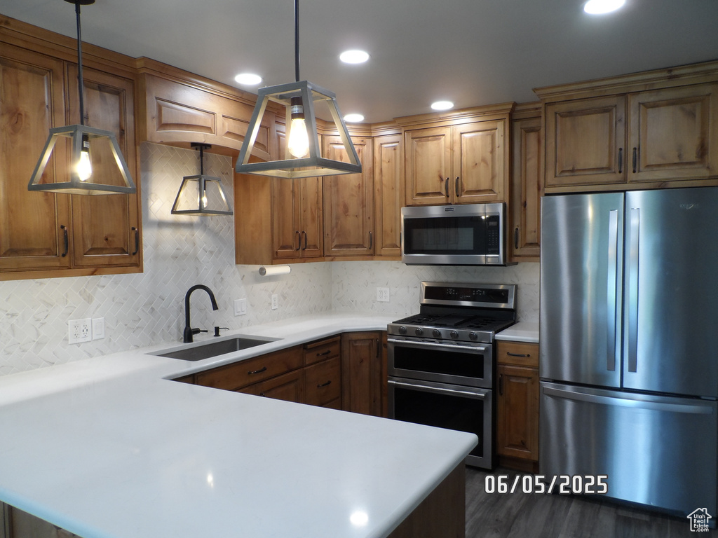 Kitchen featuring appliances with stainless steel finishes, a sink, light countertops, decorative backsplash, and recessed lighting