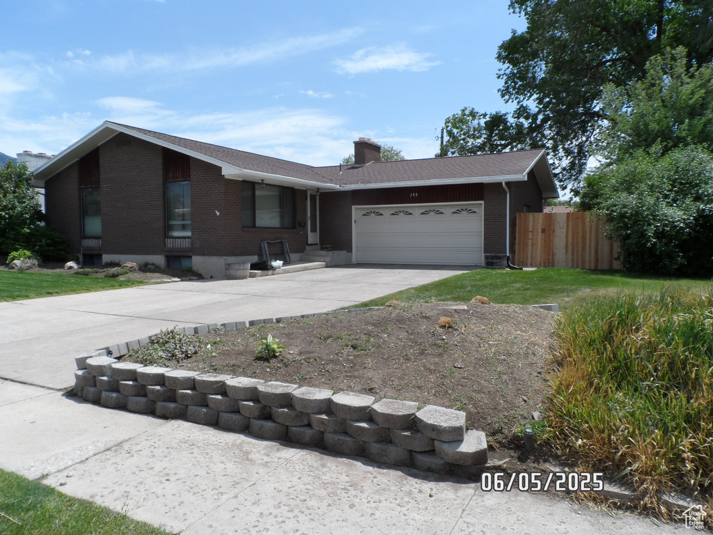 Single story home featuring brick siding, driveway, a garage, a chimney, and a shingled roof