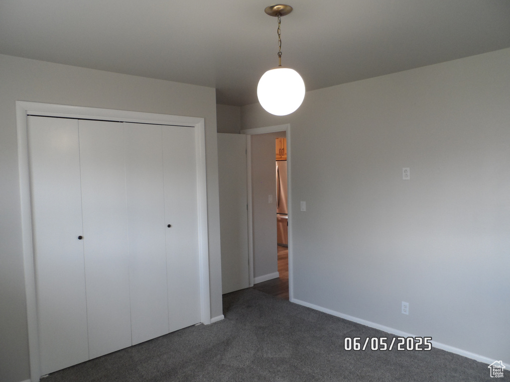 Unfurnished bedroom with a closet, dark carpet, and baseboards